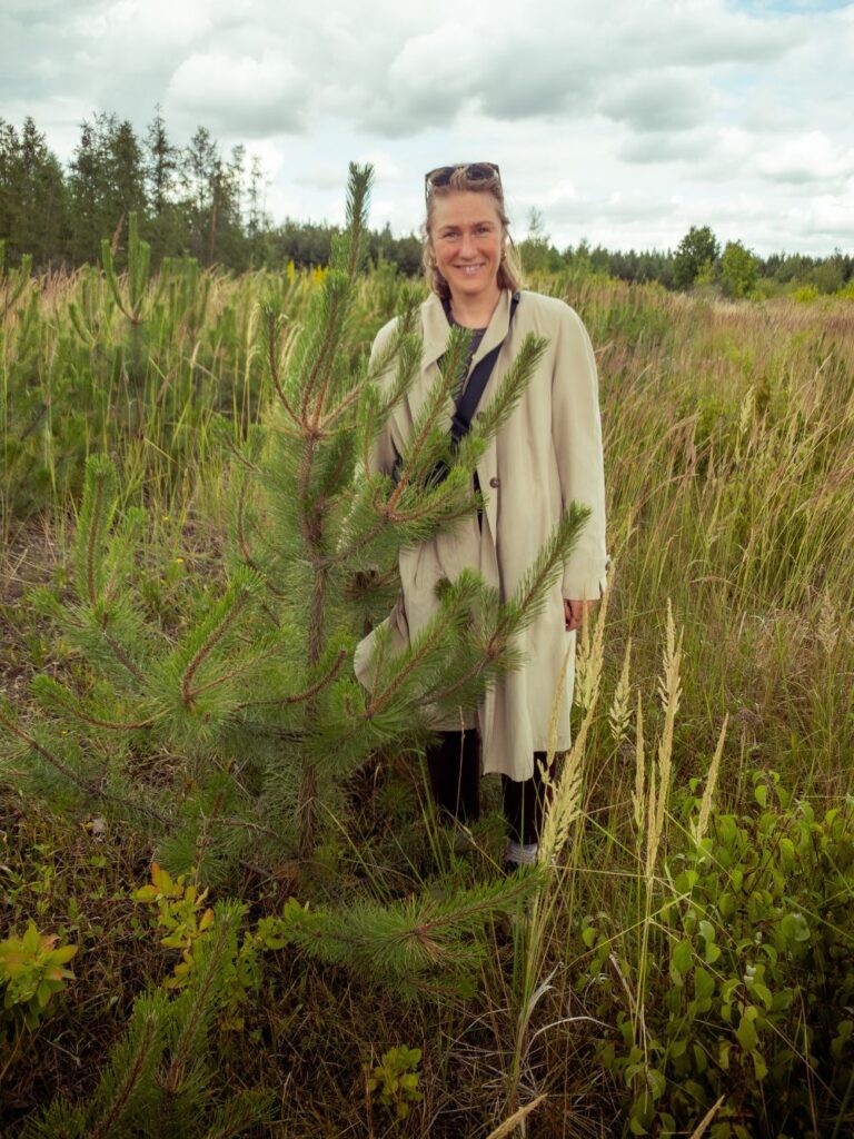Carla Hater von ForTomorrow neben einem kleinen Baum